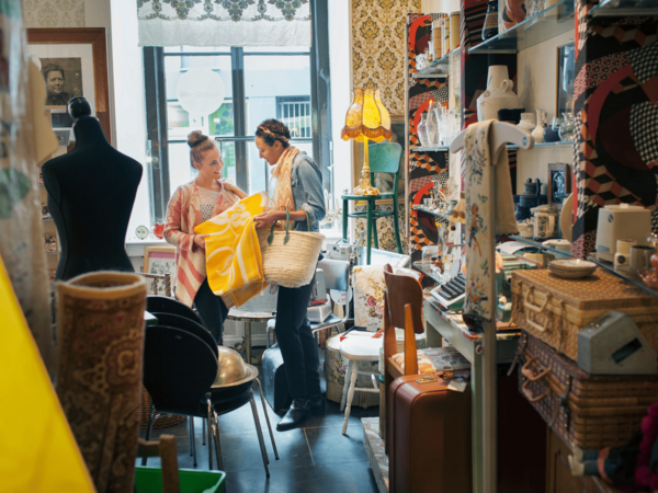 Twee vrouwen in een tweedehandswinkel bekijken een kleed.